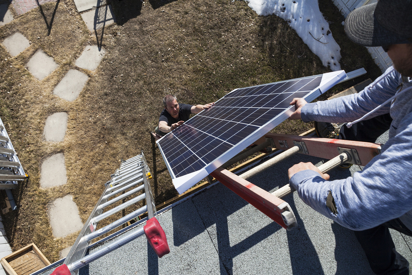 Ouvrier pose de panneaux solaires photovoltaïques sur toit incliné Energreen