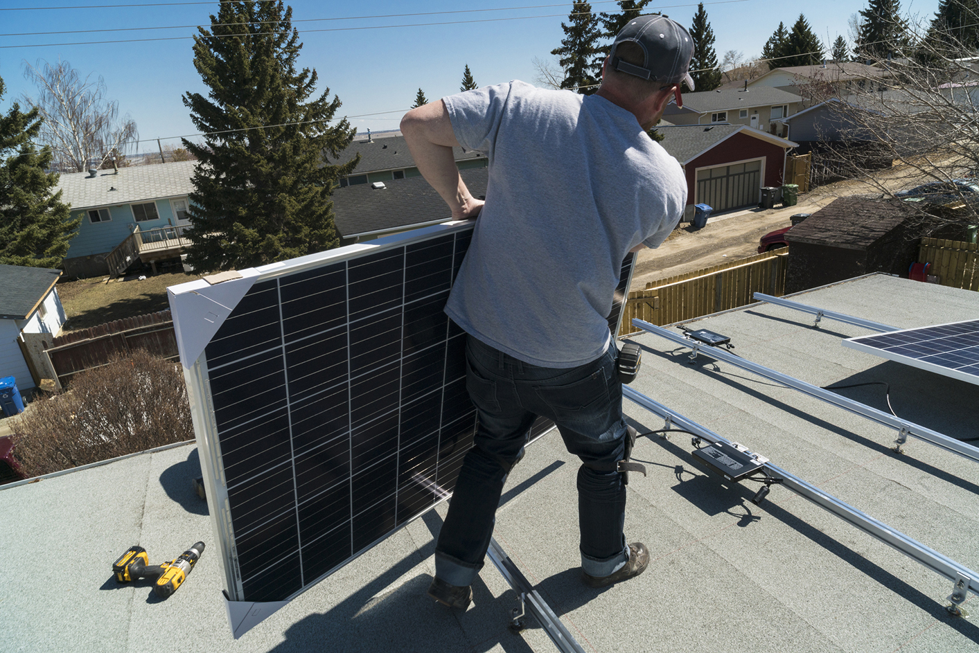 Ouvrier pose de panneaux solaires photovoltaïques sur toit plat Energreen